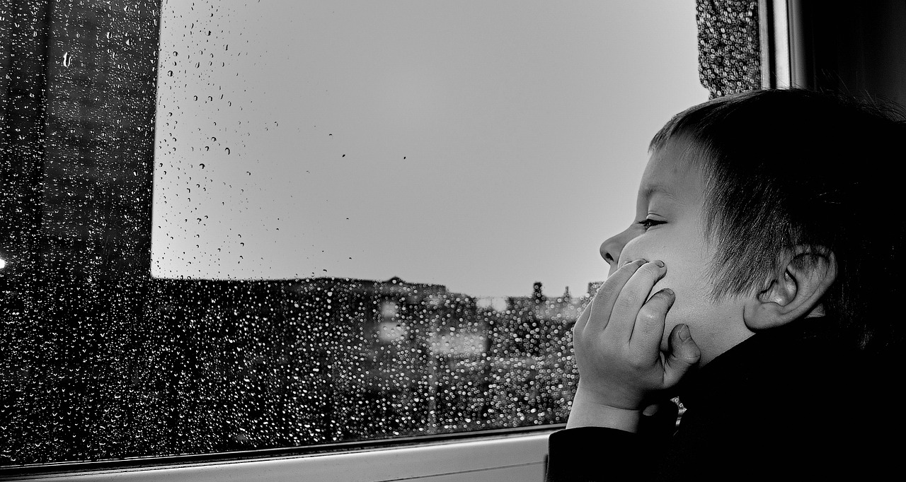 Kid looking at the rainy window