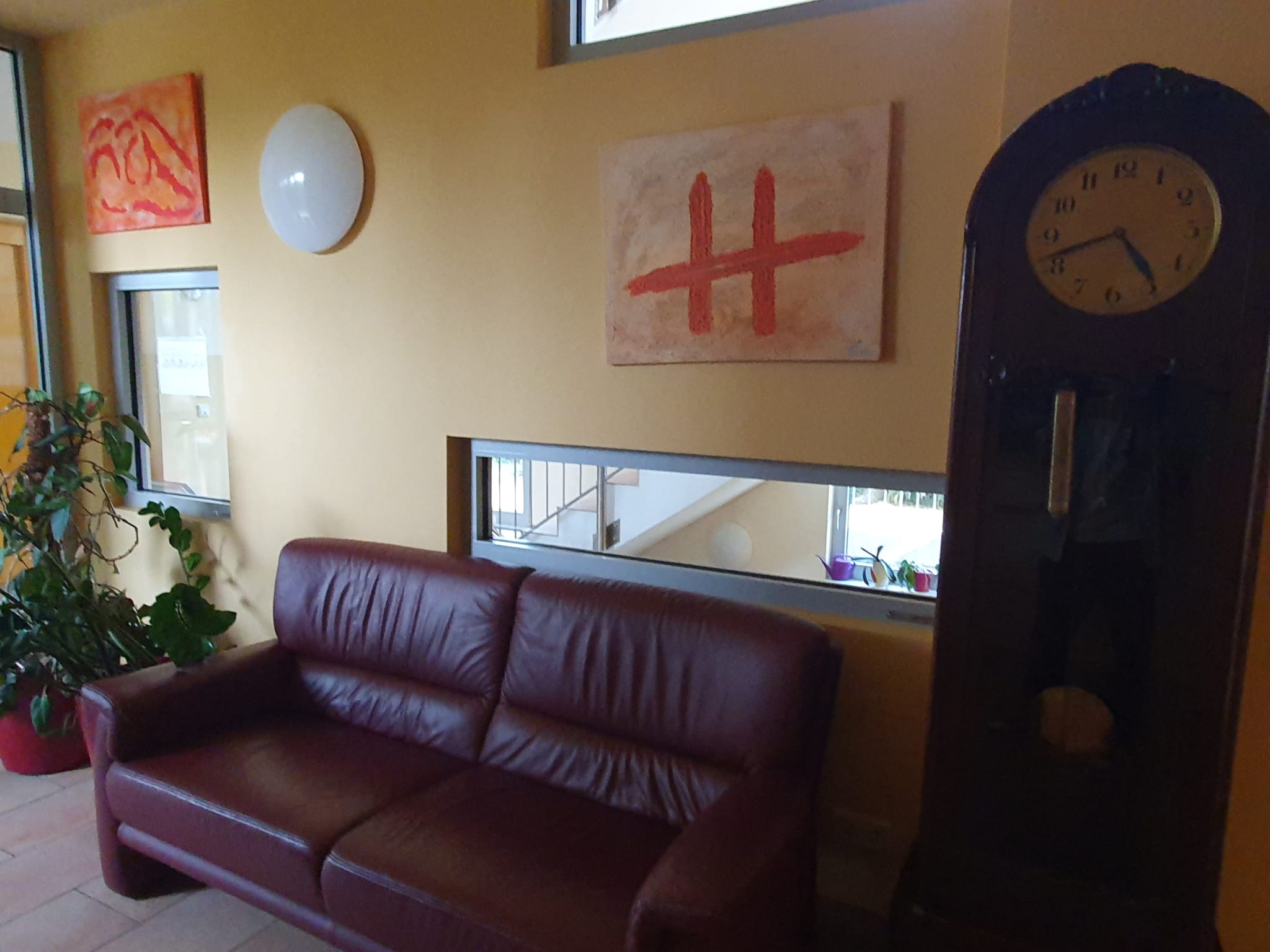 Ein Aufenthaltsbereich im Hospiz Lebensbrücke, mit einer Couch und kunstvollen Gemälden, die den Raum gestalten.