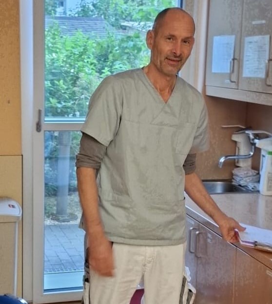 Pflegekraft in blauer Arbeitsuniform.