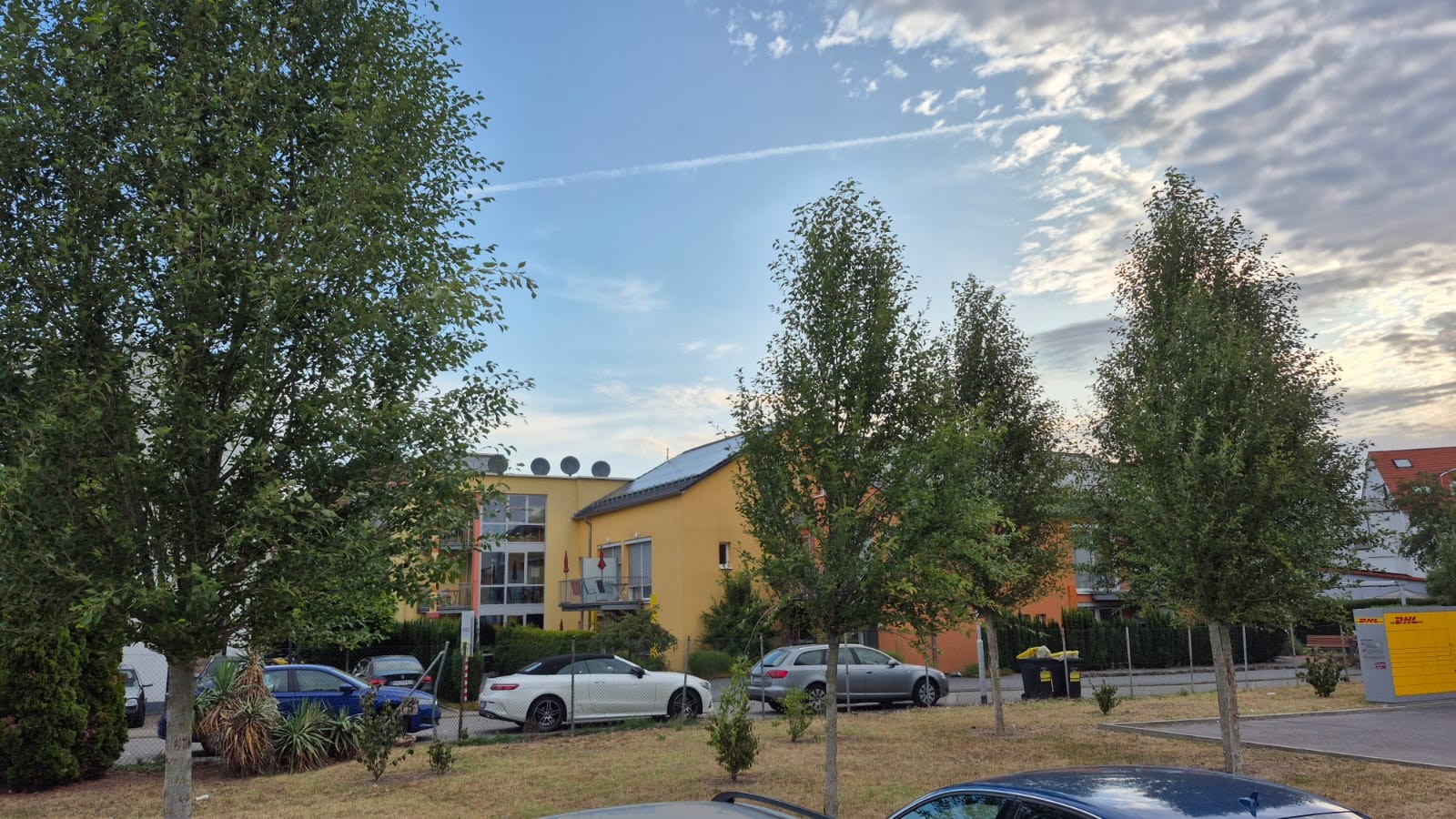 Blick auf das Hospiz Lebensbrücke bei Tageslicht, umgeben von vielen Autos und grünen Bäumen.